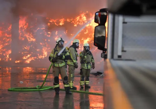 Feuerwehrleute mit Strahlrohr beim Löschen eines Großbrandes