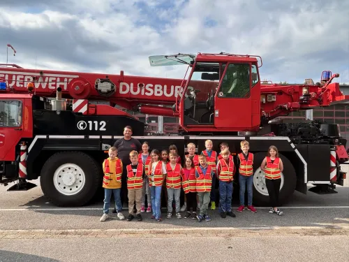 Gruppe der Kinderfeuerwehr steht vor einem Feuerwehr-Kranwagen